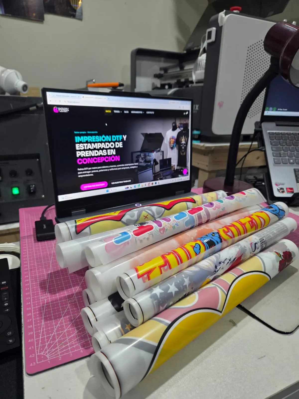 Paños DTF impresos enrollados sobre la mesa de trabajo de Fénix Creations